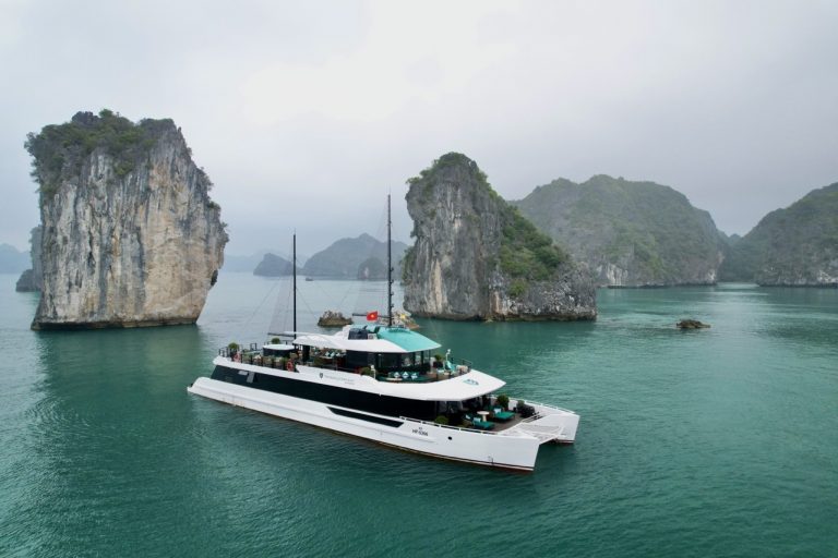 Stunning Lan Ha Bay scenery with a luxury cruise boat and towering limestone islands.