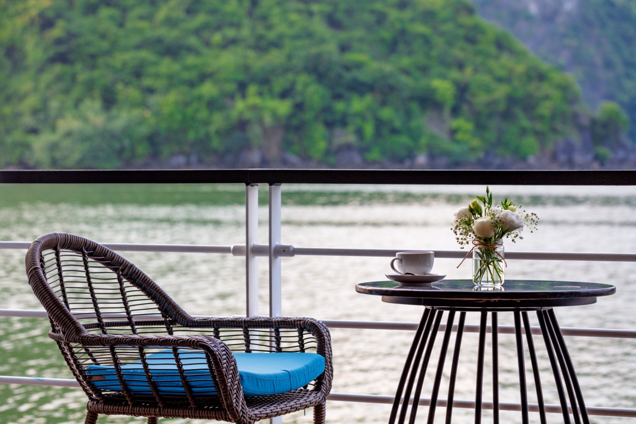 Stunning view from a cruise balcony in Halong Bay with serene waters and lush green islands.