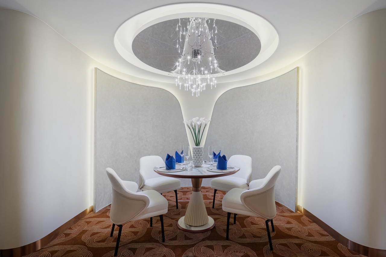 Elegant modern dining room with white chairs and a round table, perfect for luxury travel experiences.