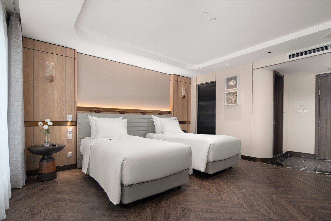 Modern hotel room with two white beds, stylish decor, and wooden accents for a luxurious stay.