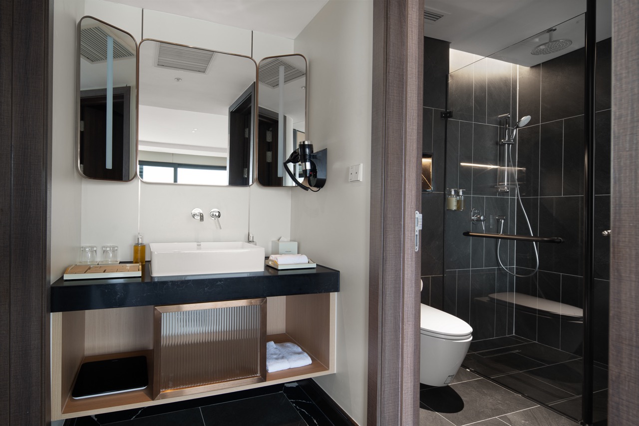 Luxurious modern hotel bathroom with stylish black and white decor and spacious shower area.