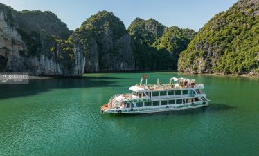 Boat cruising through Lan Ha Bay surrounded by towering limestone karsts, showcasing tranquil waters.