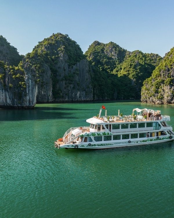 Boat cruising through Lan Ha Bay surrounded by towering limestone karsts, showcasing tranquil waters.
