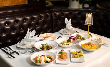 Luxurious dining setup on Halong Bay cruise with elegant tableware and gourmet dishes.