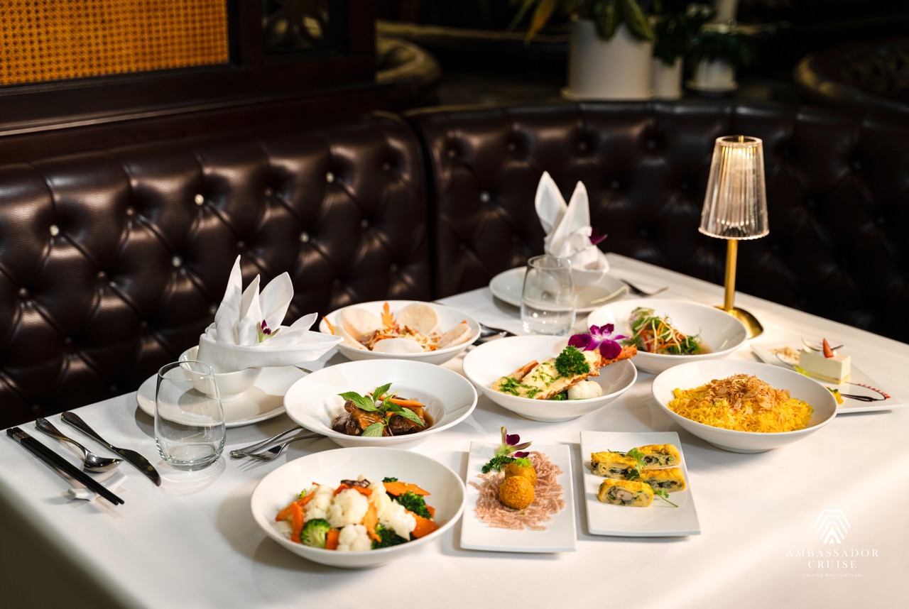 Luxurious dining setup on Halong Bay cruise with elegant tableware and gourmet dishes.