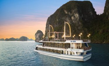 Cruise ship sailing in Halong Bay with stunning limestone karsts at sunset.