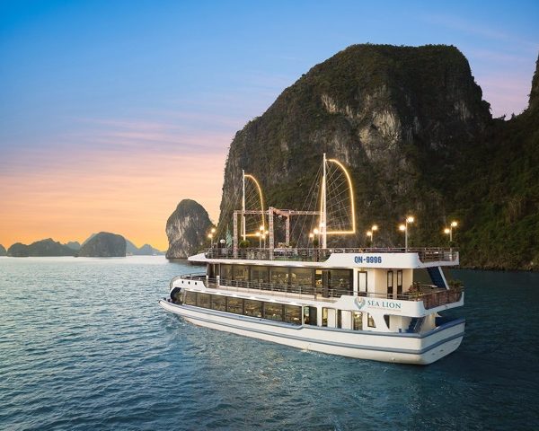 Cruise ship sailing in Halong Bay with stunning limestone karsts at sunset.