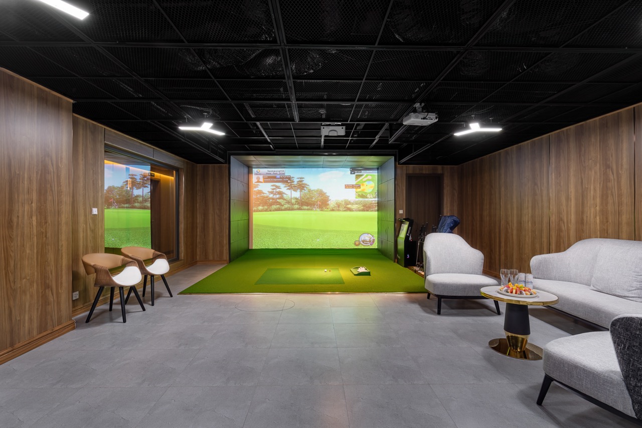 Indoor golf simulator room with high-tech screen and comfortable seating, perfect for golf practice and entertainment.