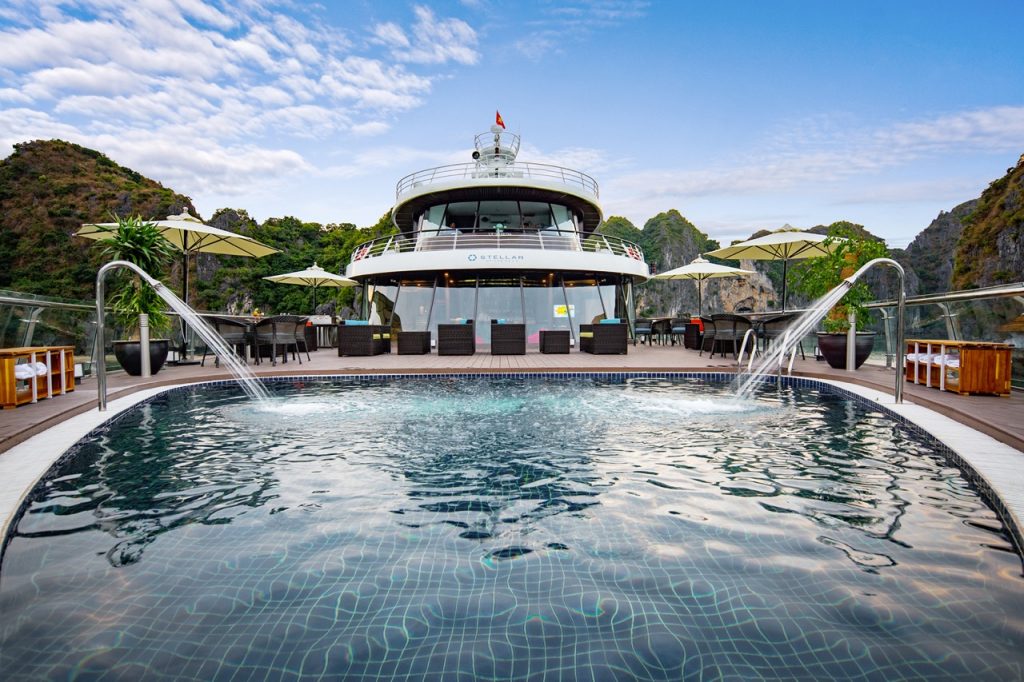 Luxurious yacht with swimming pool and scenic mountain views in Halong Bay, Vietnam.