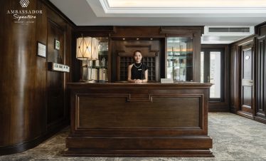 Elegant cruise reception with wooden decor and welcoming staff in Halong Bay.