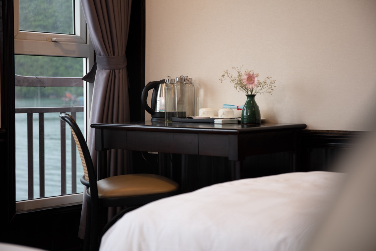 Comfortable river-view hotel room with tea set and flower decoration for a relaxing stay at ViettrendTour.