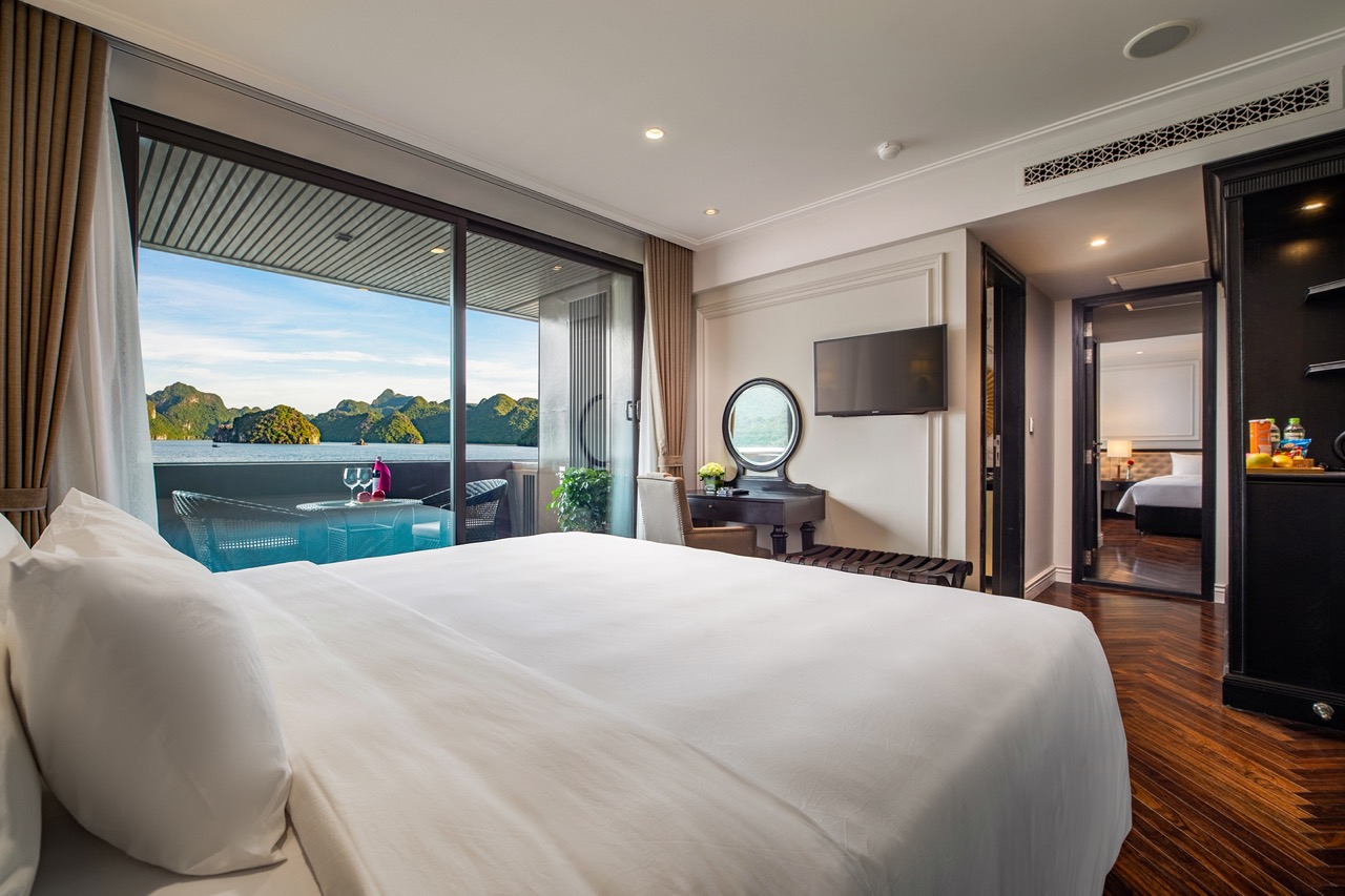 Luxury hotel room with balcony view of mountain landscape and ocean scenery, modern amenities, and elegant decor.