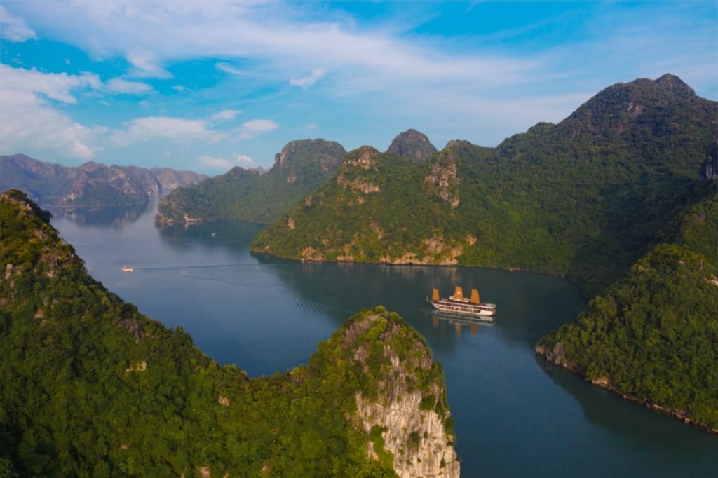 Stunning view of Halong Bay with lush green islands and calm waters from a cruise balcony.