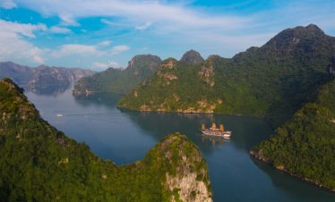 Stunning view of Halong Bay with lush green islands and calm waters from a cruise balcony.