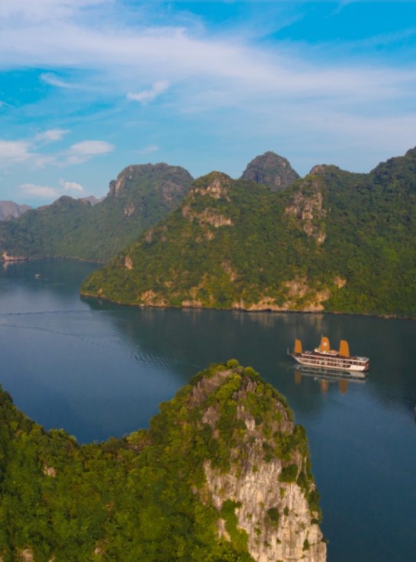 Stunning view of Halong Bay with lush green islands and calm waters from a cruise balcony.