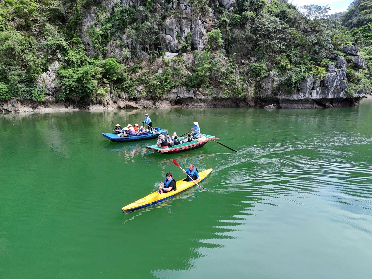 Kayaking in Lan Ha Bay with lush green cliffs and calm waters, perfect for adventure and relaxation.