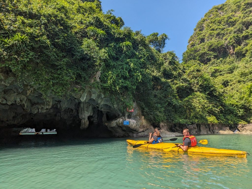 Kayaking adventure in Lan Ha Bay with lush green cliffs and clear turquoise waters.