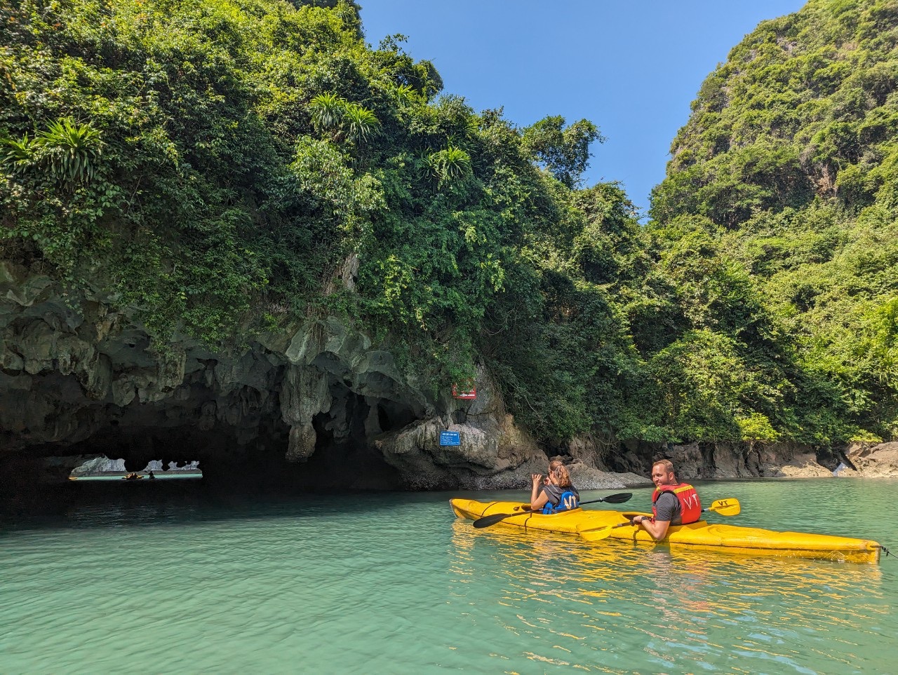 Kayaking adventure in Lan Ha Bay with lush green cliffs and clear turquoise waters.