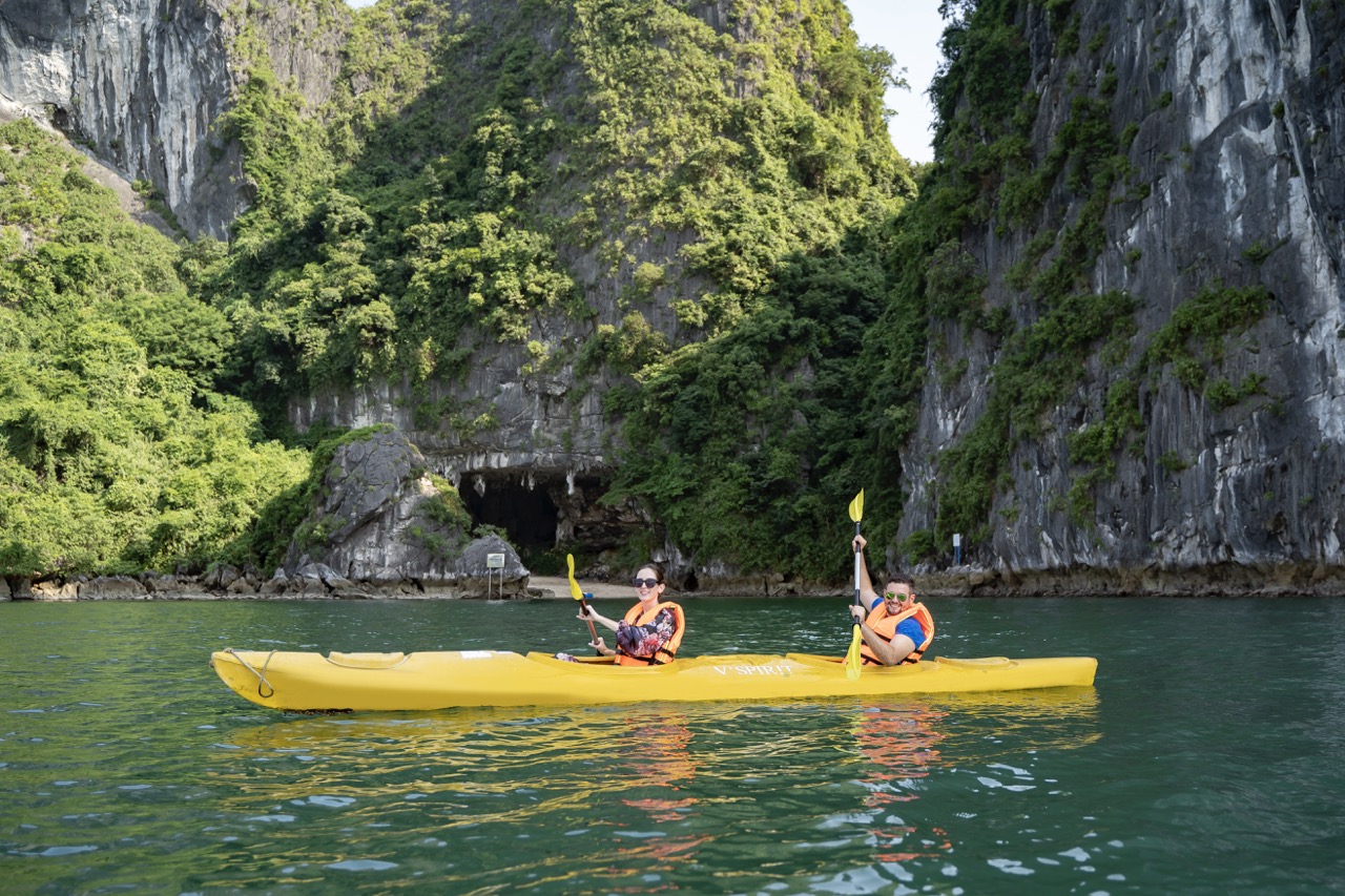 ViettrendTour - Scenic kayaking adventure in emerald green waters and lush limestone cliffs.