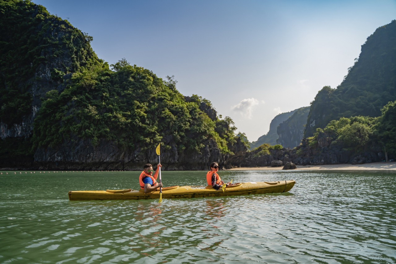 Tranquil kayak ride through lush green limestone islands and clear waters in Vietnam.
