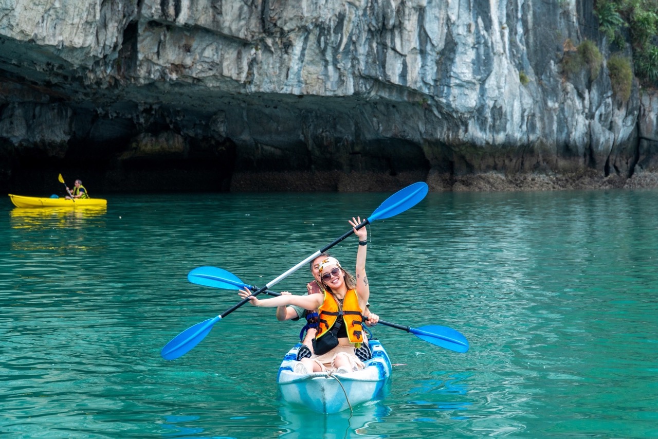 Kayaking in clear turquoise water near rocky cliffs, outdoor adventure activity in Vietnam.