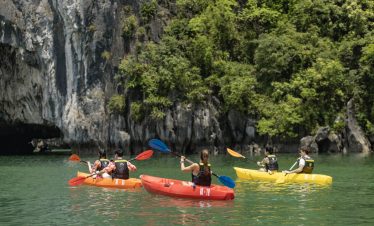 Kayaking in Halong Bay with lush cliffs and emerald waters, perfect for an adventurous travel experi.