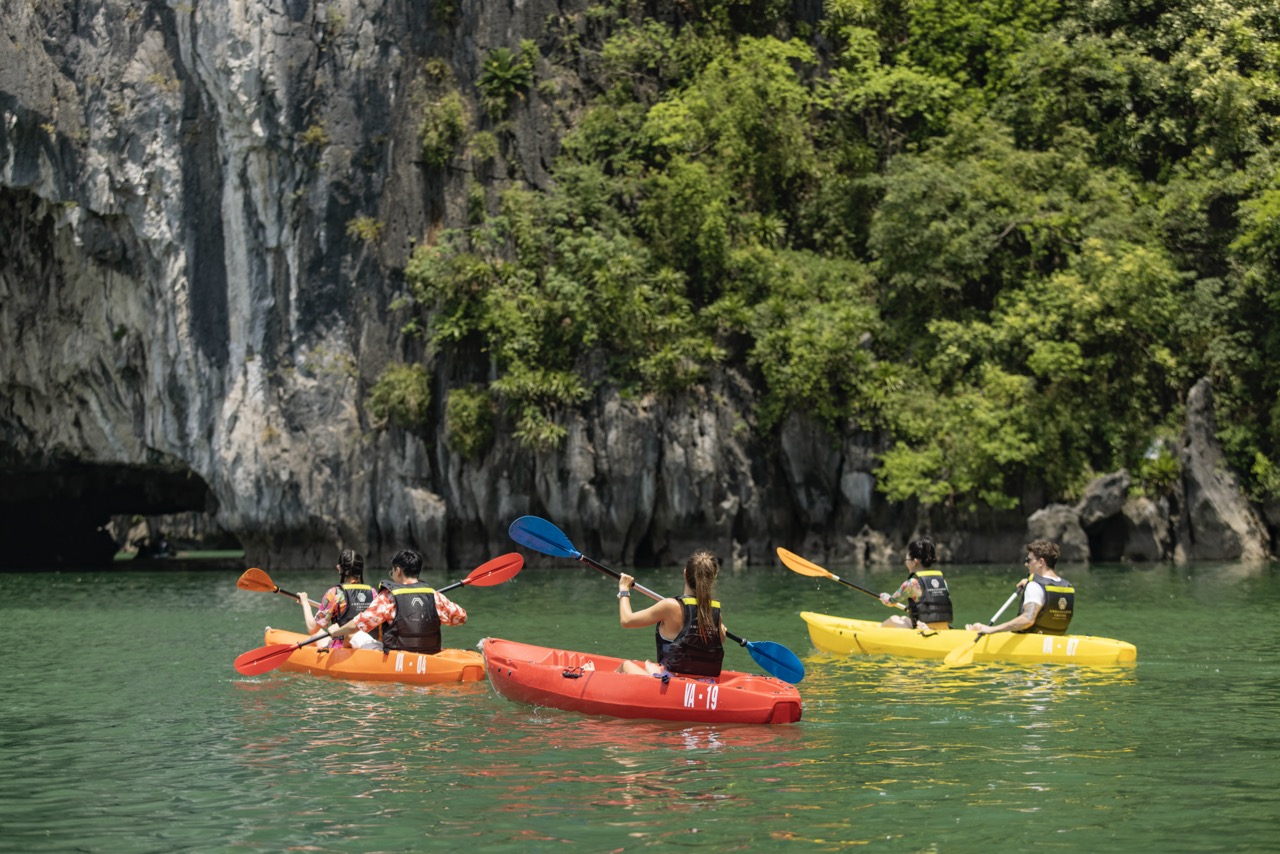 Kayaking in Halong Bay with lush cliffs and emerald waters, perfect for an adventurous travel experi.