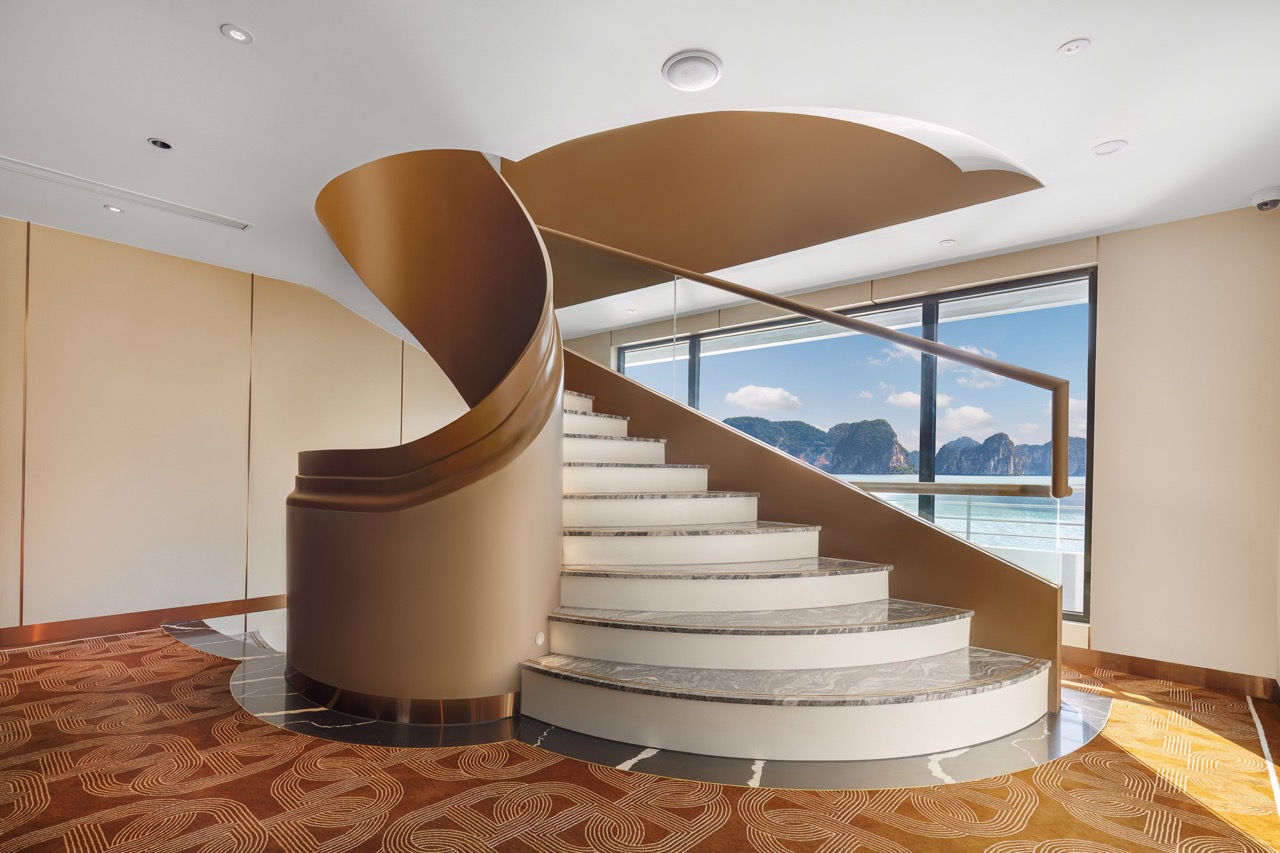 Luxurious spiral staircase with sea view in modern hotel interior.