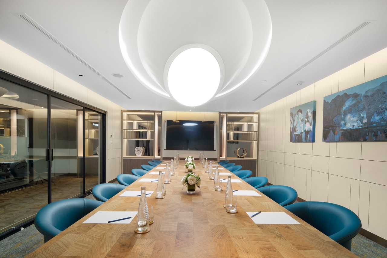 Elegant modern conference room with wooden table and blue chairs for business meetings.