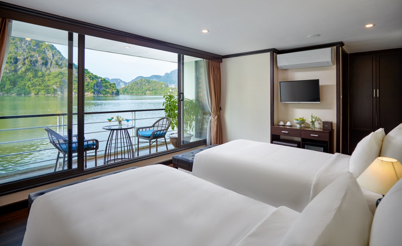 Stunning view from a cruise balcony overlooking Halong Bay with lush islands and calm waters.