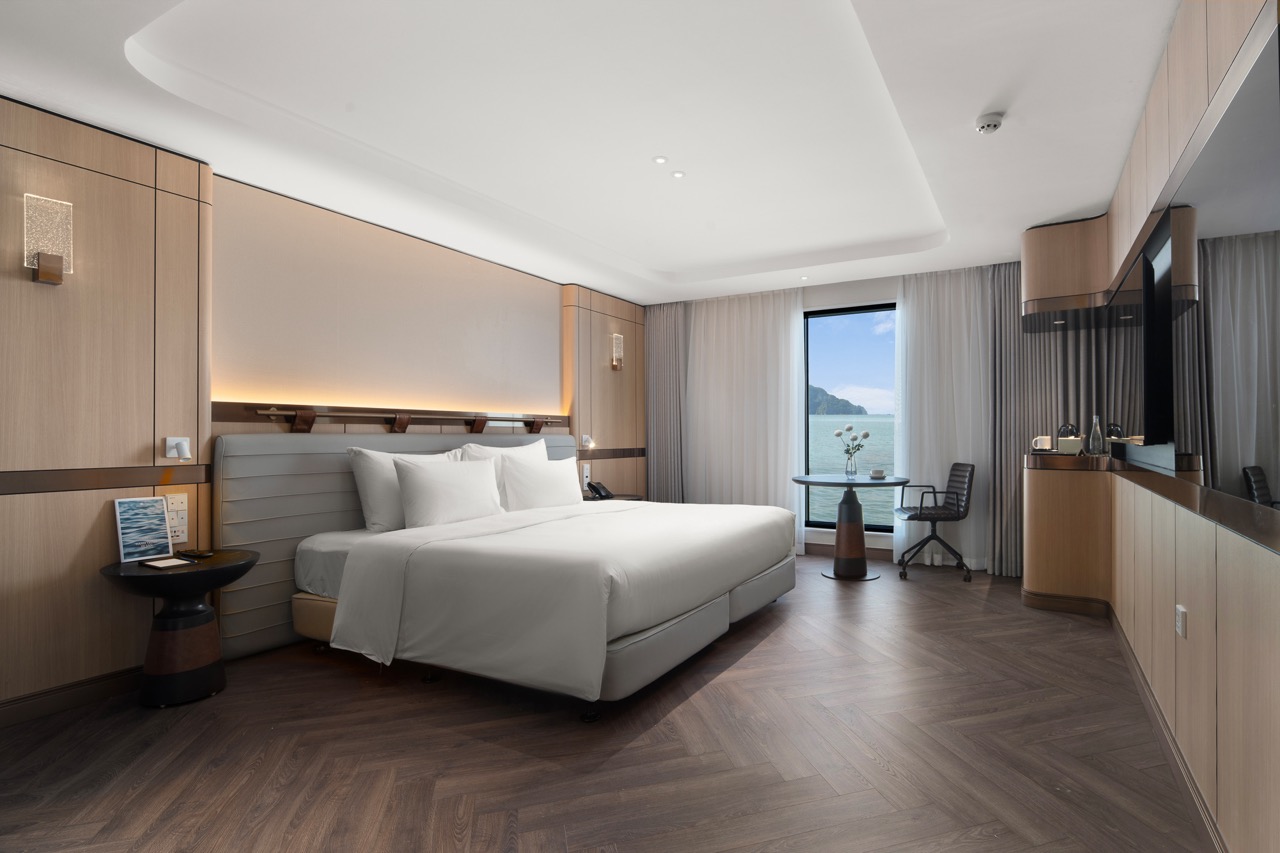 Luxury ocean-view hotel room with modern decor and balcony overlooking water.
