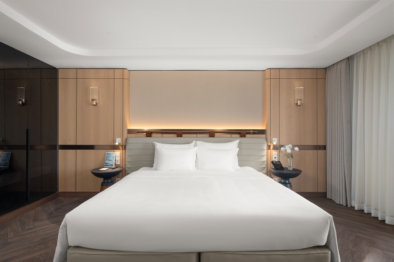 Luxury hotel bedroom with modern design, white linens, and soft lighting for a comfortable stay.