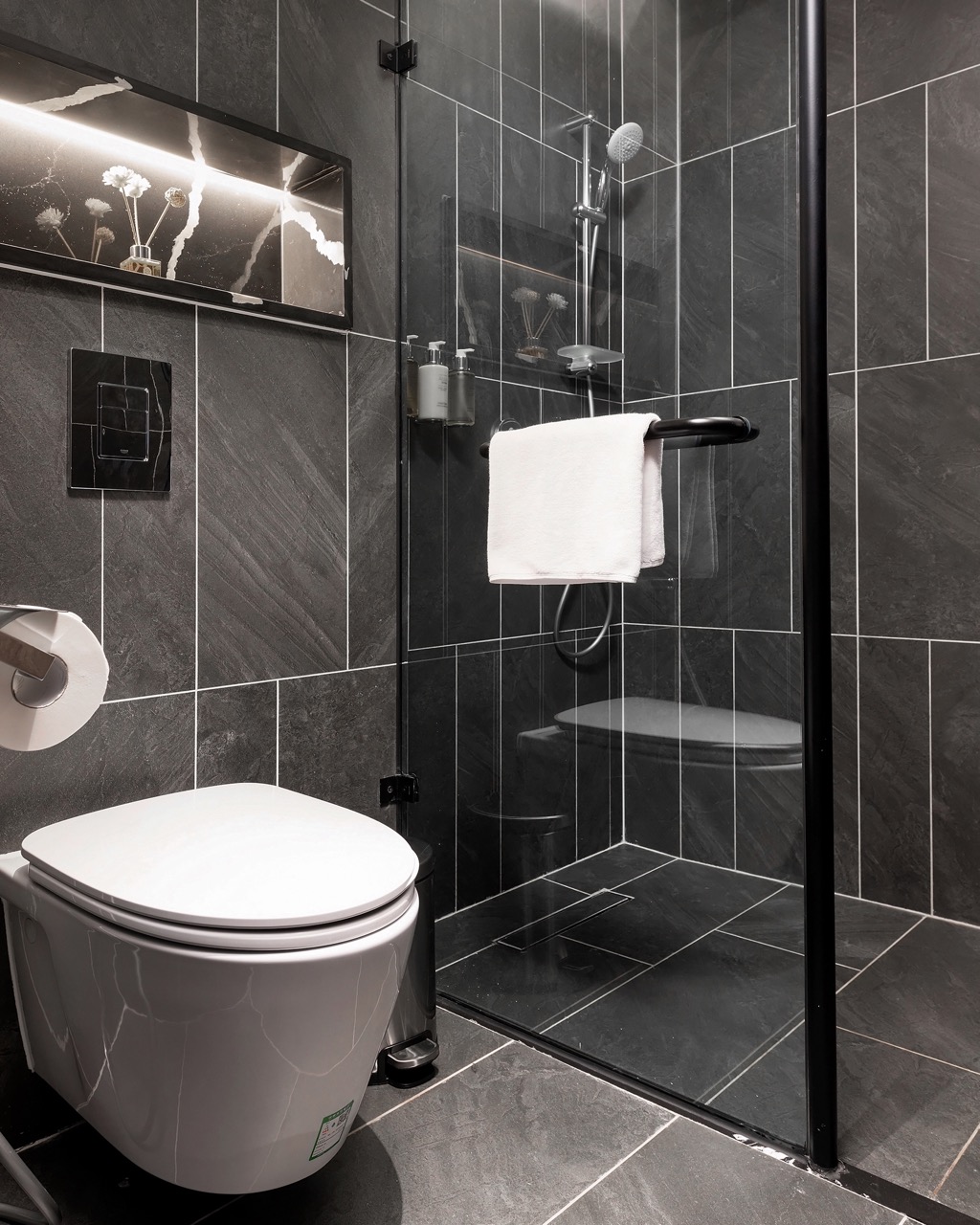 Modern black tiled bathroom with walk-in shower and sleek toilet, stylish fixtures for luxury comfort.