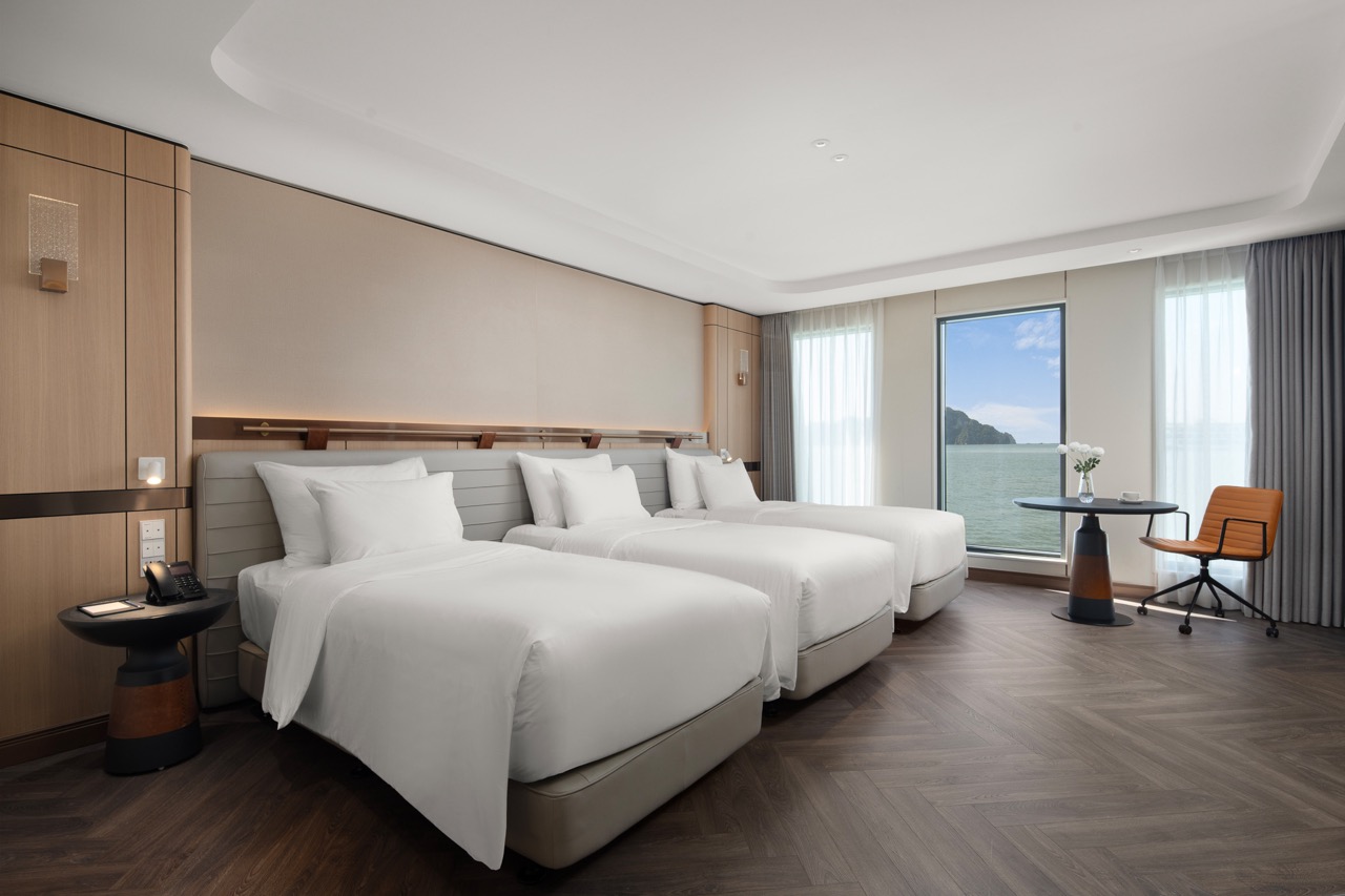 Elegant hotel room with ocean view, three cozy beds & modern decor, perfect for relaxing stay in Vietnam.