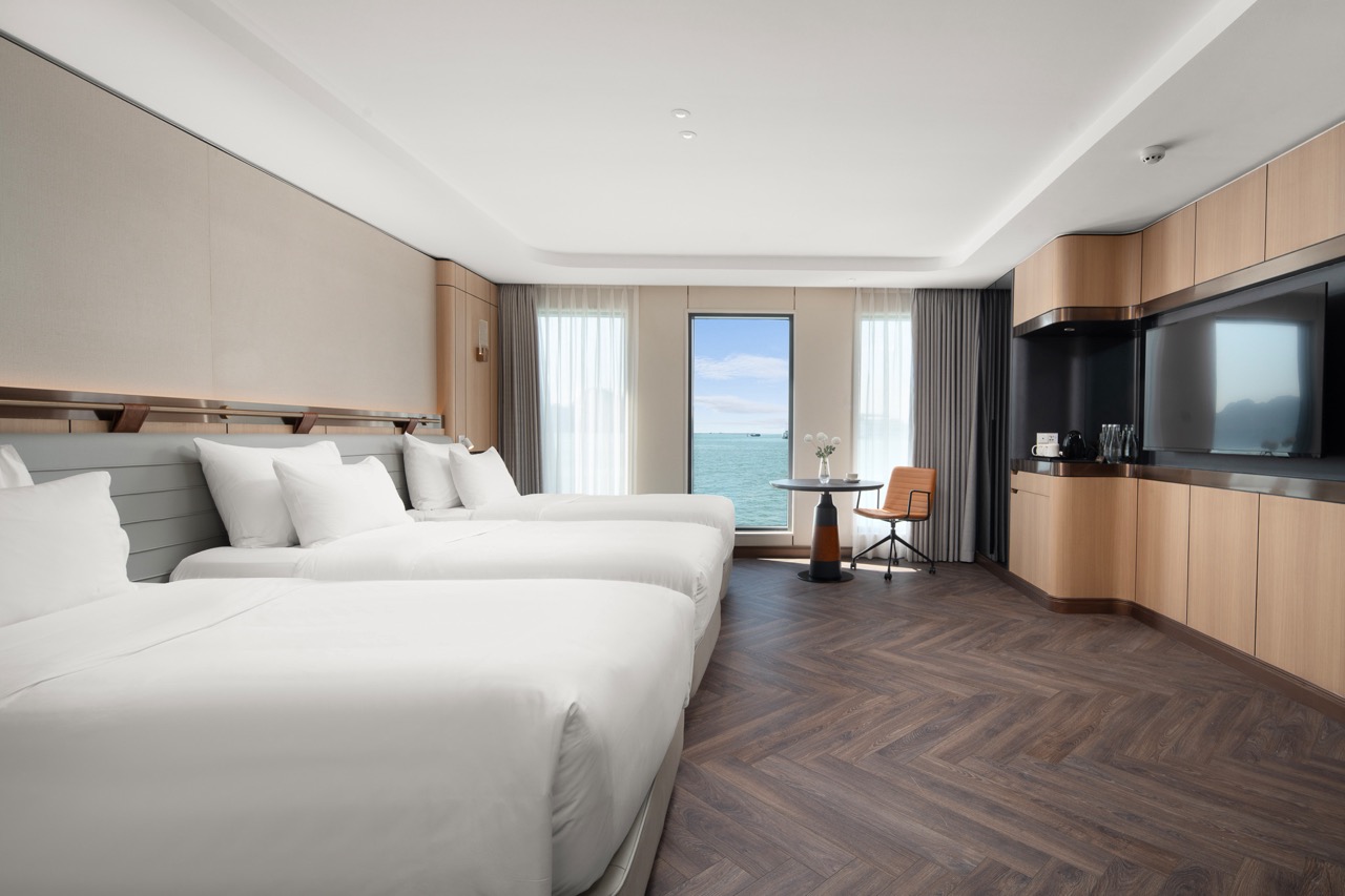 Bright ocean-view hotel room with modern decor, spacious beds, and amenities in Vietnam.