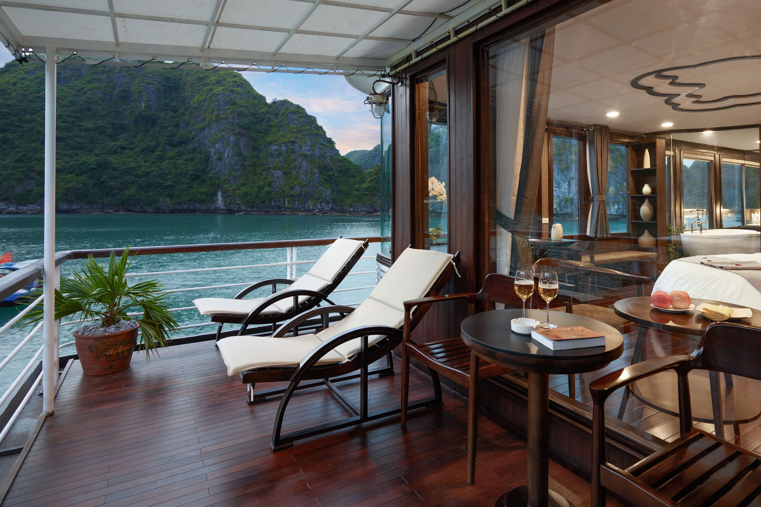 Luxurious cruise balcony with scenic mountain view and relaxing recliner chairs in Vietnam.