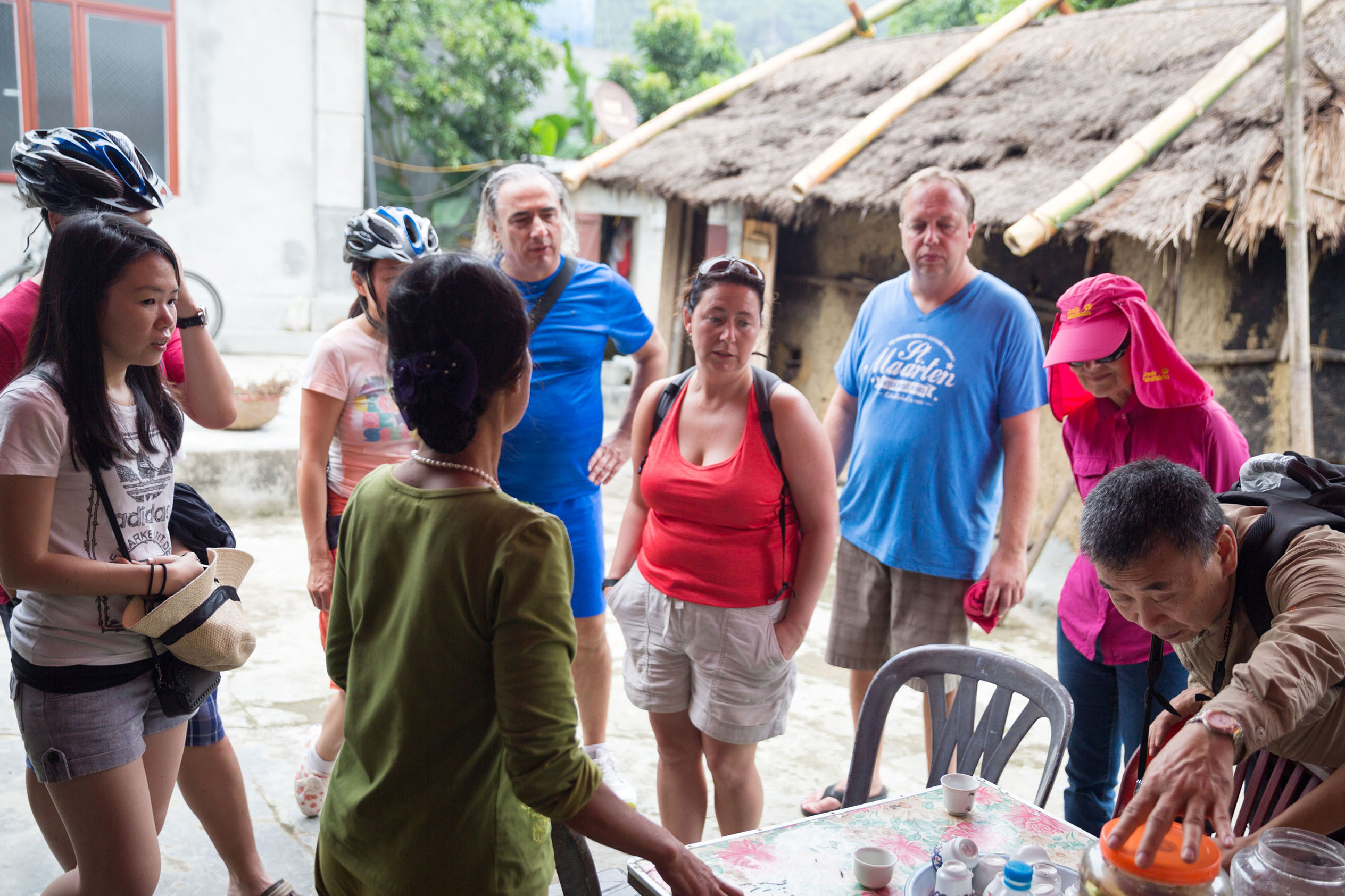 Friendly tour group receiving cultural explanation in rural Vietnam, high-quality travel experience with ViettrendTour.