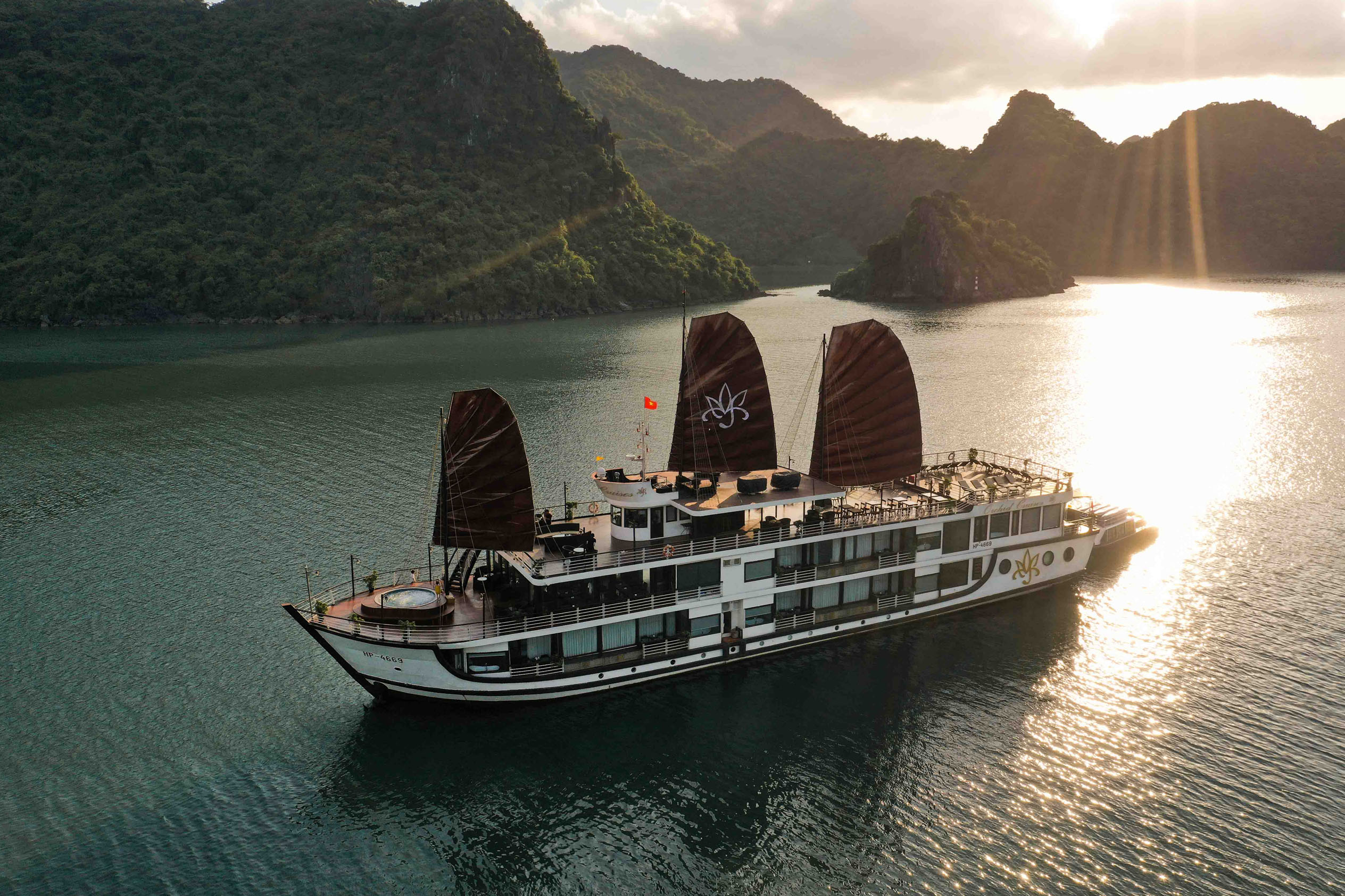 Elegant cruise ship sailing through Halong Bay at sunset.