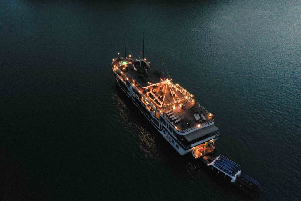 Elegant night cruise ship decorated with lights on calm water in Vietnam.