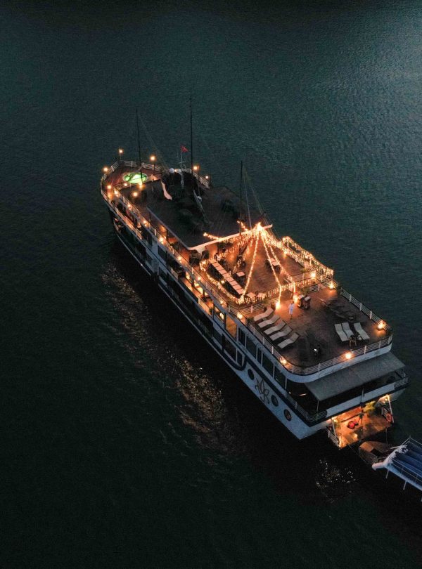 Elegant night cruise ship decorated with lights on calm water in Vietnam.