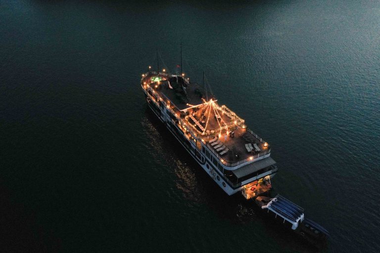 Elegant night cruise ship decorated with lights on calm water in Vietnam.