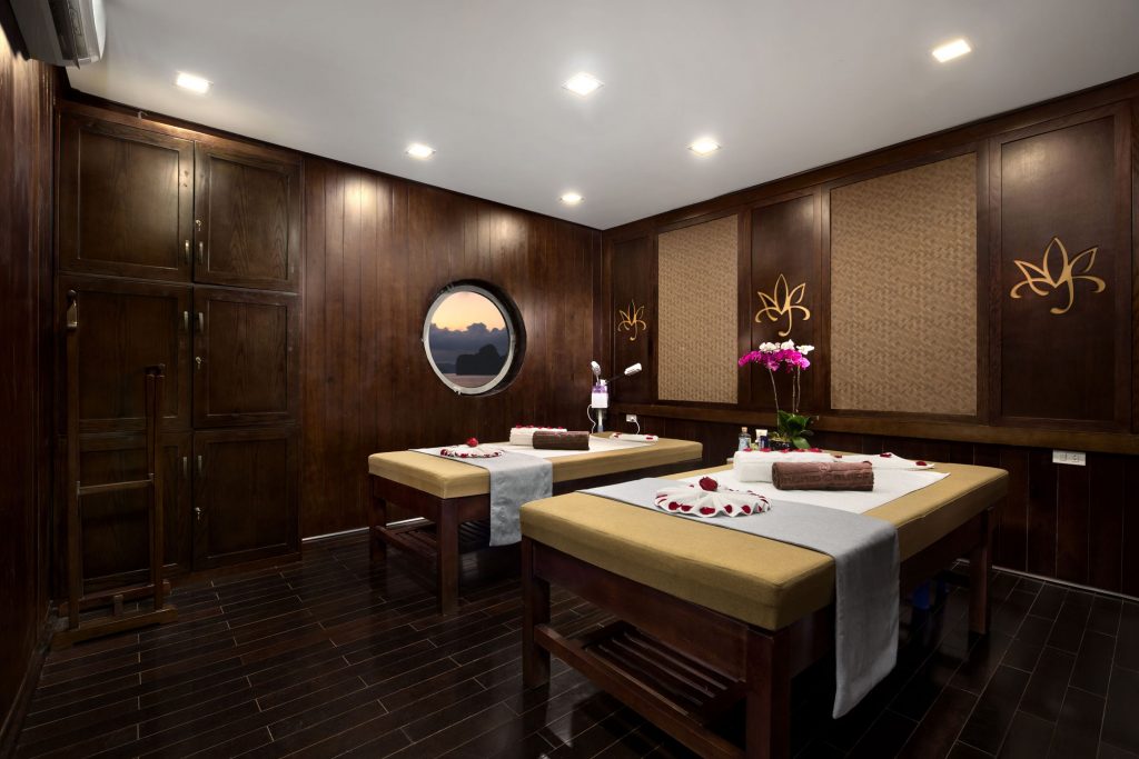 Relaxing spa massage room with wooden walls, soft lighting, and floral decor at ViettrendTour spa.