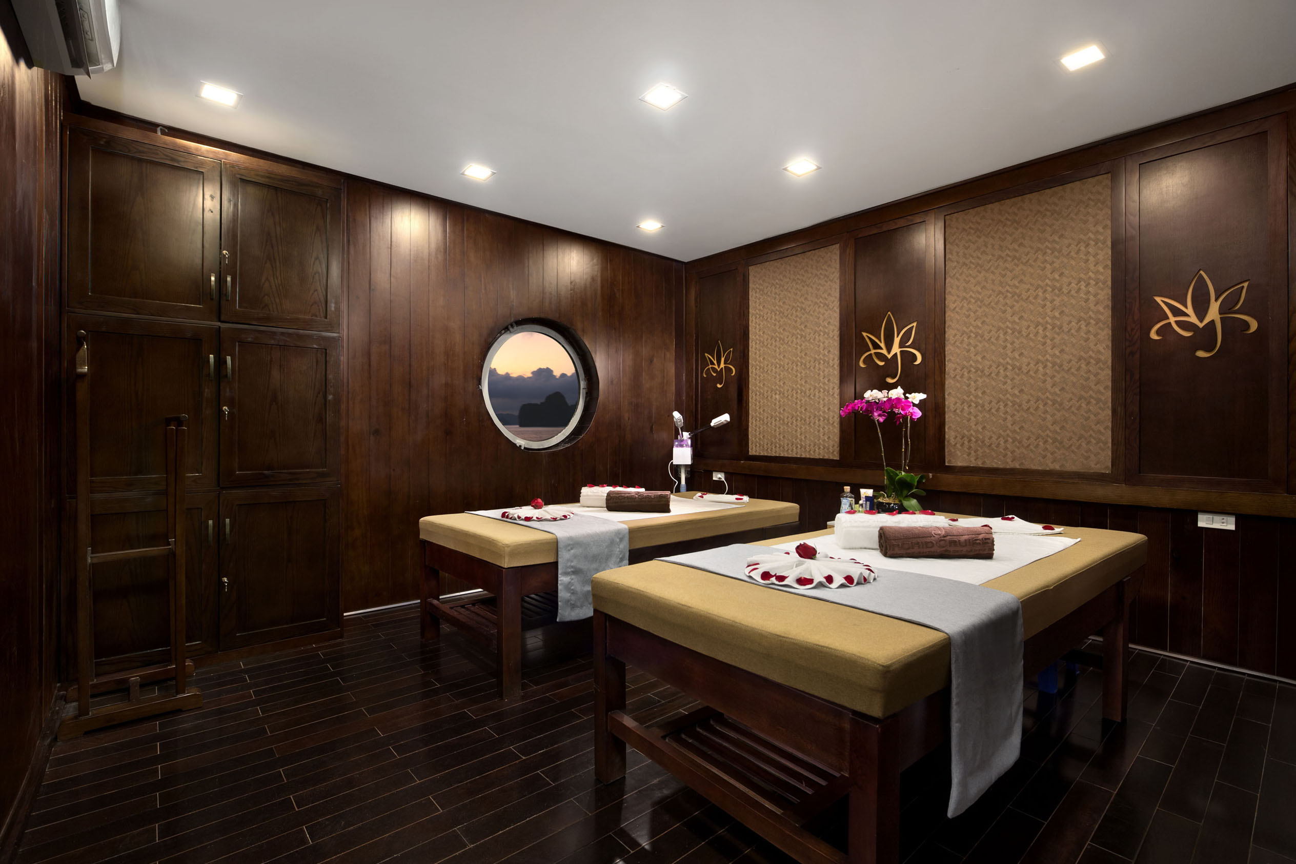 Relaxing spa massage room with wooden walls, soft lighting, and floral decor at ViettrendTour spa.