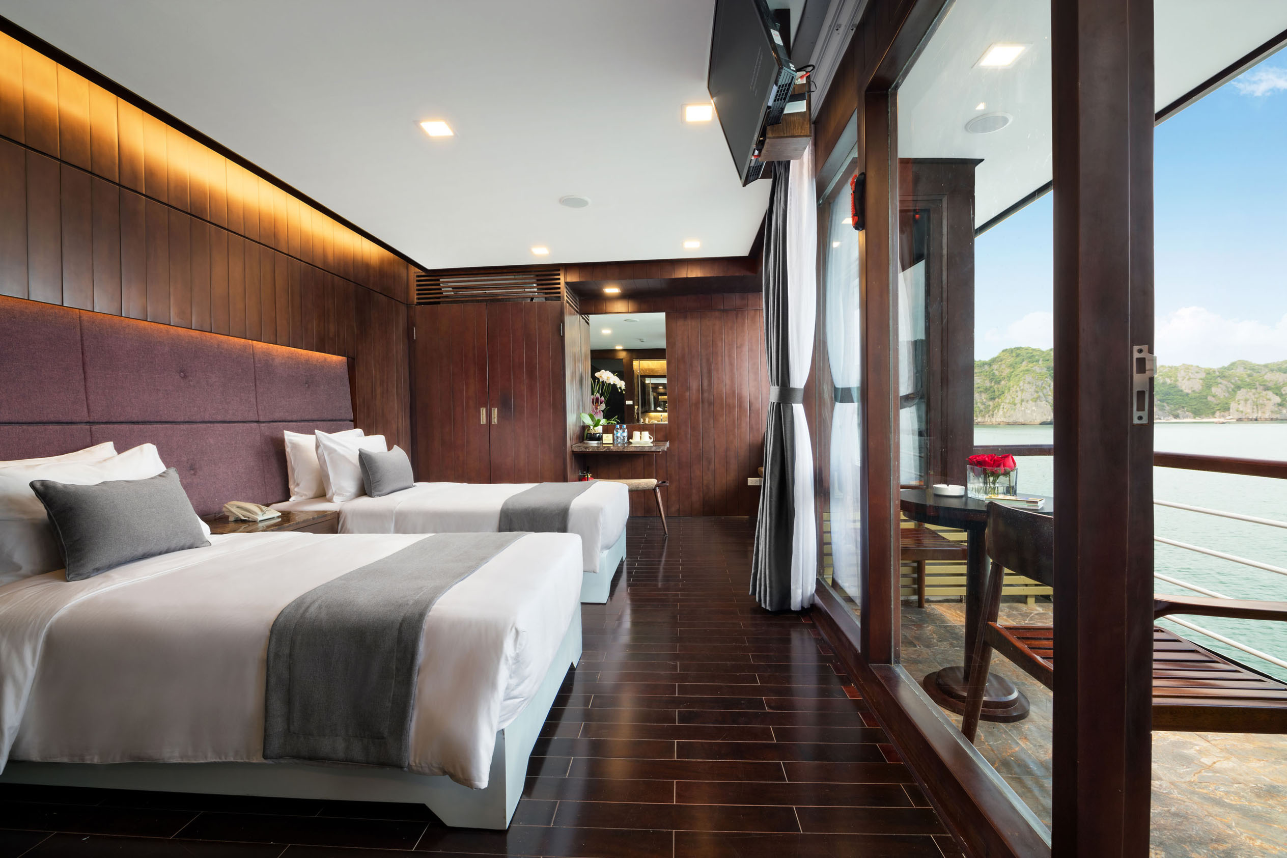 Elegant hotel room with ocean view and balcony, modern furnishings, and warm wood accents for a relaxing stay.