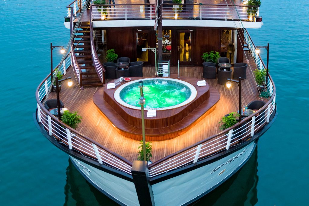 Luxury cruise ship with hot tub and outdoor seating on deck.