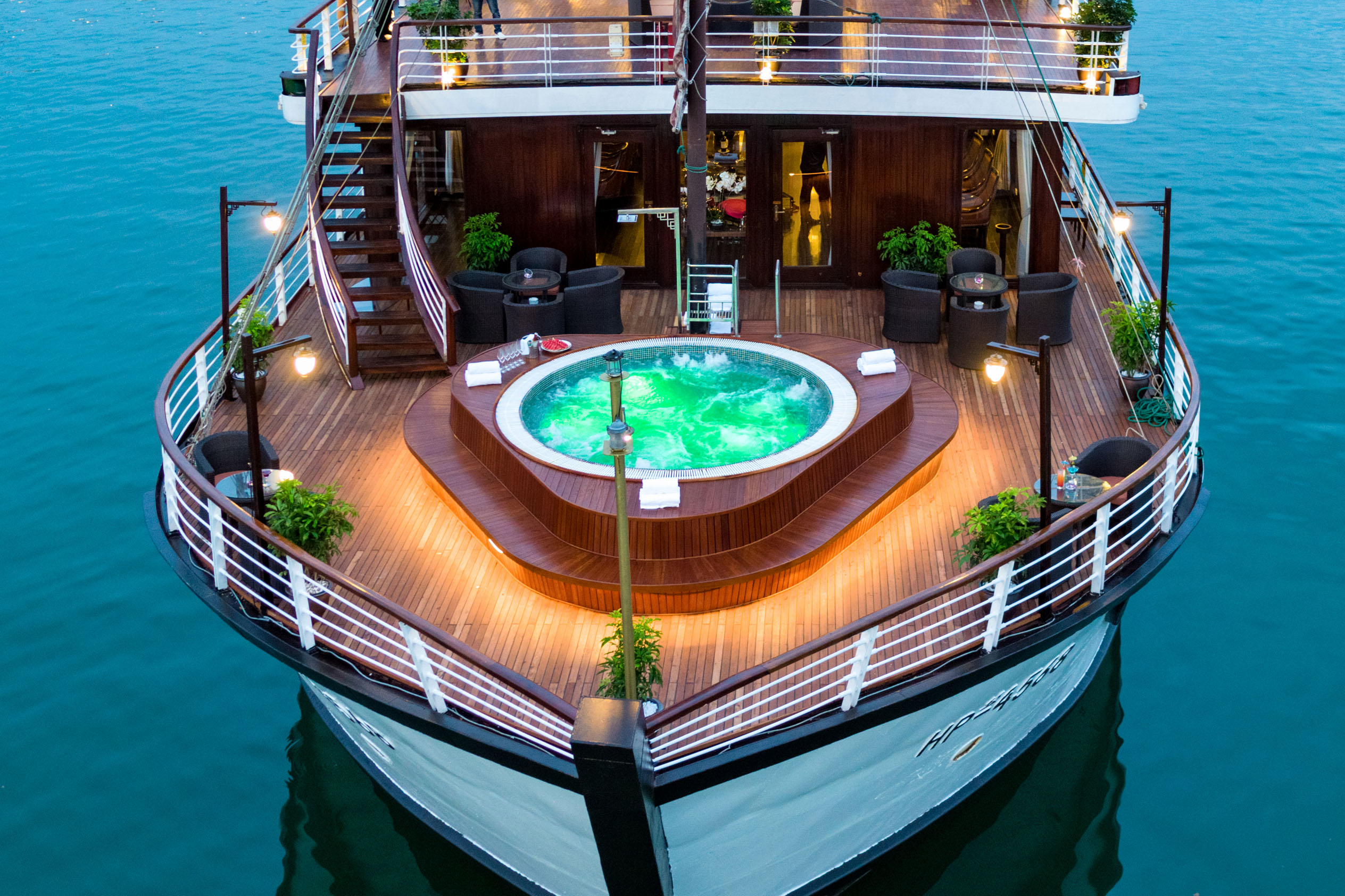 Luxury cruise ship with hot tub and outdoor seating on deck.