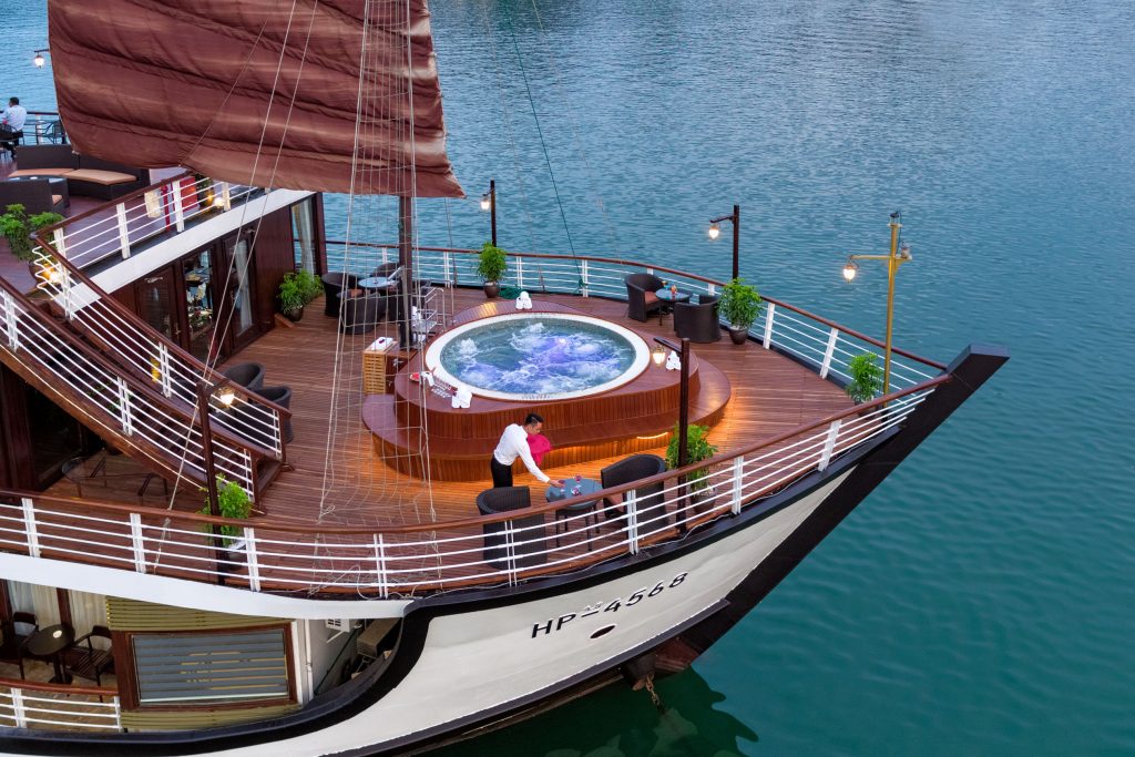 Luxurious cruise ship deck with hot tub and seaside dining, perfect for Vietnam island tours.