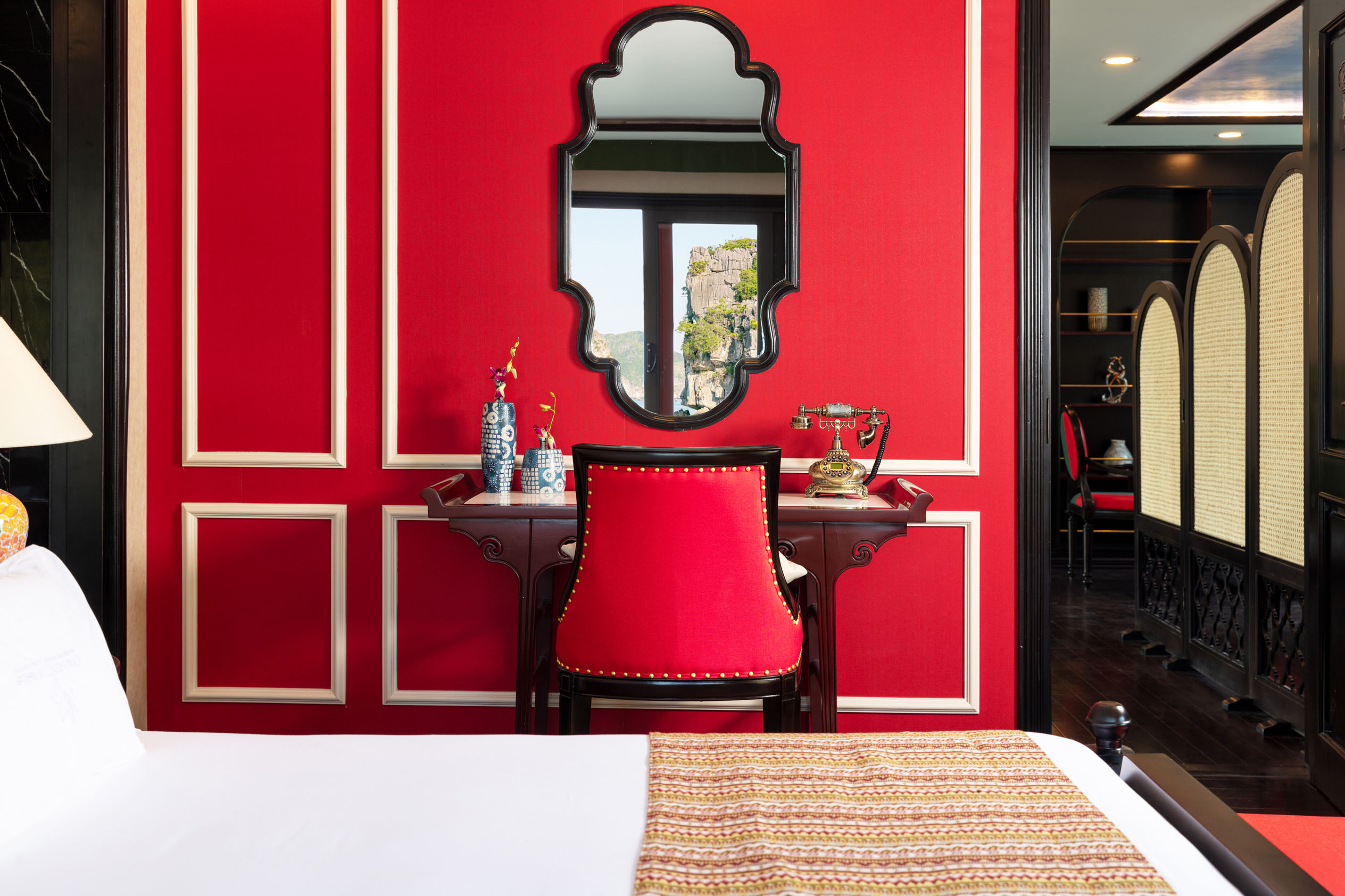 Vintage red and black hotel room interior with classic furniture and scenic view.
