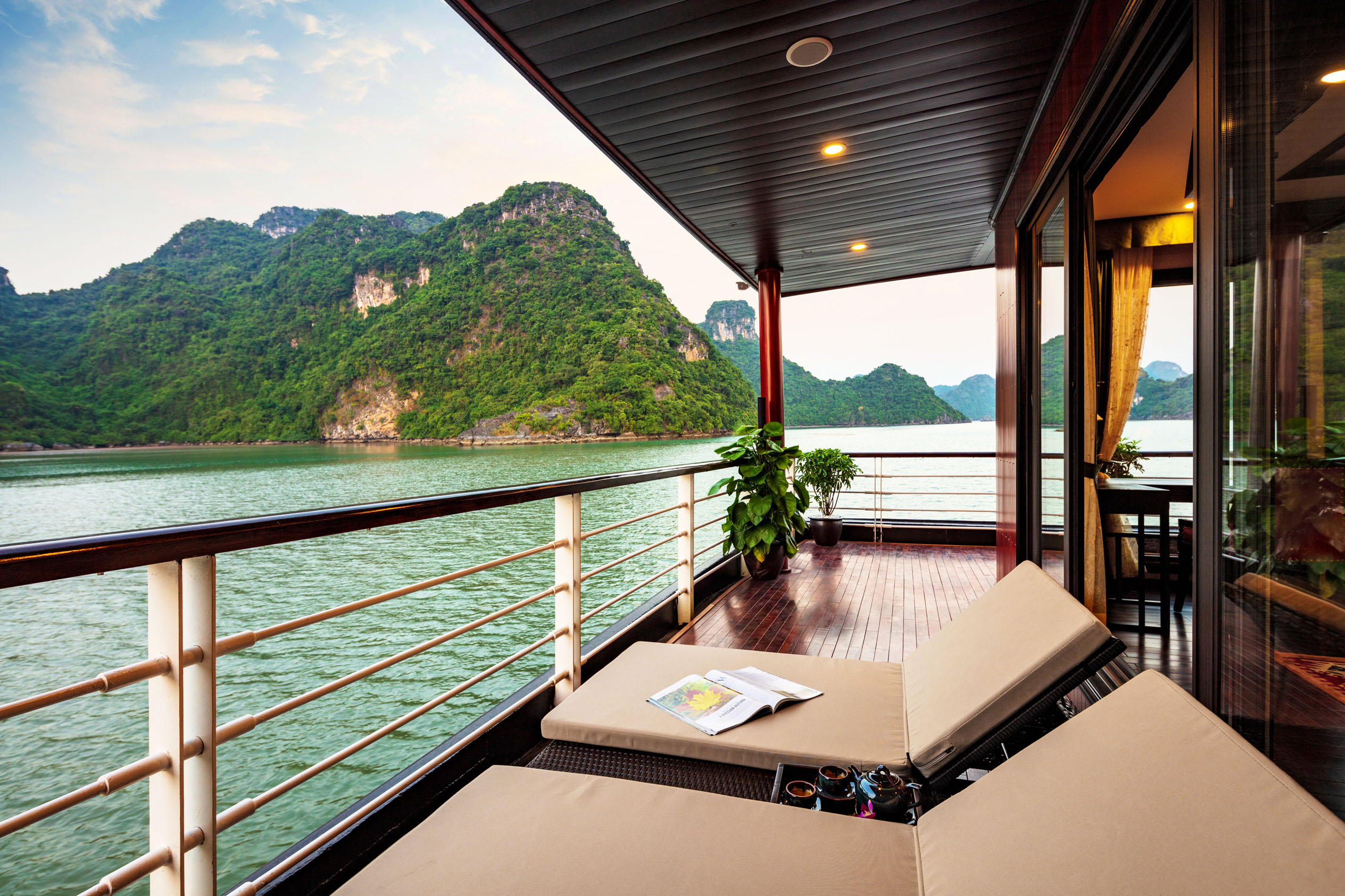 Tranquil balcony view of green mountains and river in Vietnam luxury cruise villa.