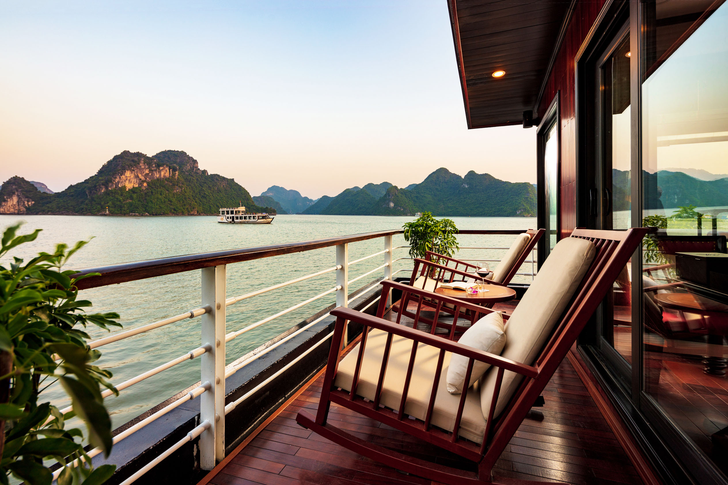 Balcony view of Halong Bay with wooden chairs and stunning island landscape, luxury Vietnam travel experience.
